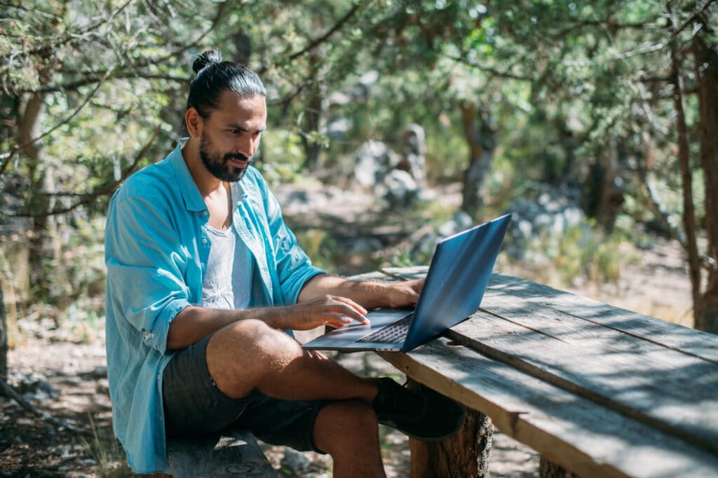 A man sitting at a picnic table working on this laptop