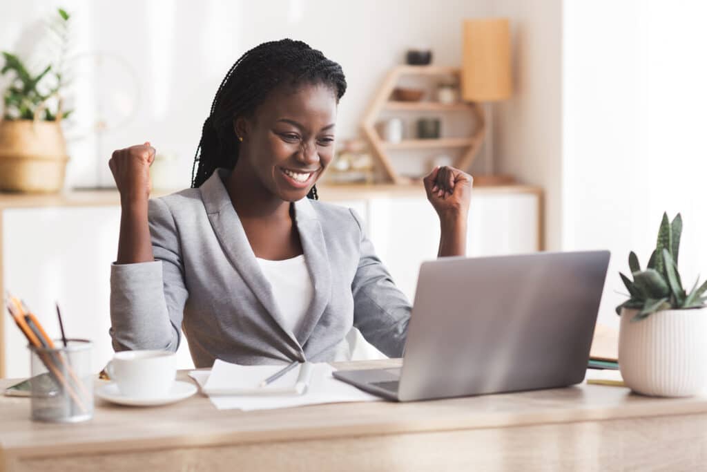 Woman sitting at a desk working on her laptop with a pen in her hand