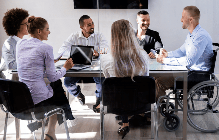 Meeting with people around a table and man in a wheel chair talking