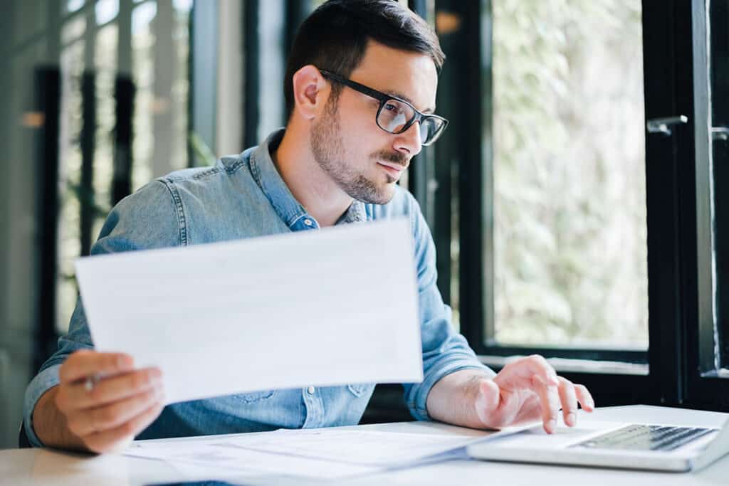 Young tax professional working on a laptop with tax return documents in an office setting